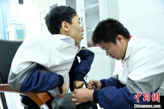 江西省南康中學(xué)北校區(qū)的高三學(xué)生朱金祥(右)正在給鐘華強(qiáng)(左)系好鞋帶。 卓忠偉 攝