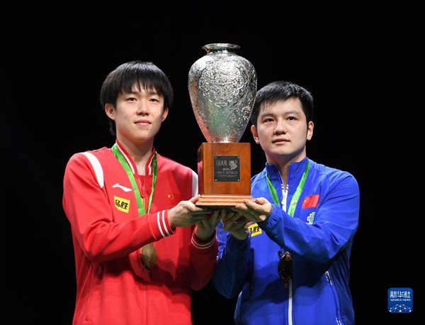 5月27日，樊振東（右）/王楚欽在頒獎儀式上高舉獎杯慶祝。當日，在南非德班進行的2023年世界乒乓球錦標賽男雙決賽中，中國組合樊振東/王楚欽以3比0戰(zhàn)勝韓國組合張禹珍/林鐘勛，奪得冠軍。新華社記者 李亞輝攝