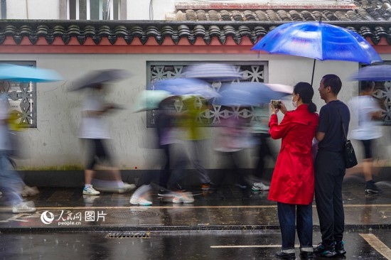 6月7日，在浙江省2023年普通高校招生考試鎮(zhèn)海中學(xué)考點，家長冒雨目送子女進入考場。人民網(wǎng) 章勇濤攝
