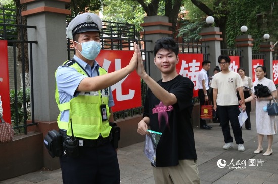 6月7日8時許，武漢中學(xué)考點門口，交警在維護秩序，并?？忌鸢耦}名。人民網(wǎng)記者 肖璐欣攝