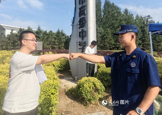 6月7日，遼寧營口老邊區(qū)消防救援大隊的消防員為高考學(xué)子加油助威。人民網(wǎng)記者 尹柏寒攝