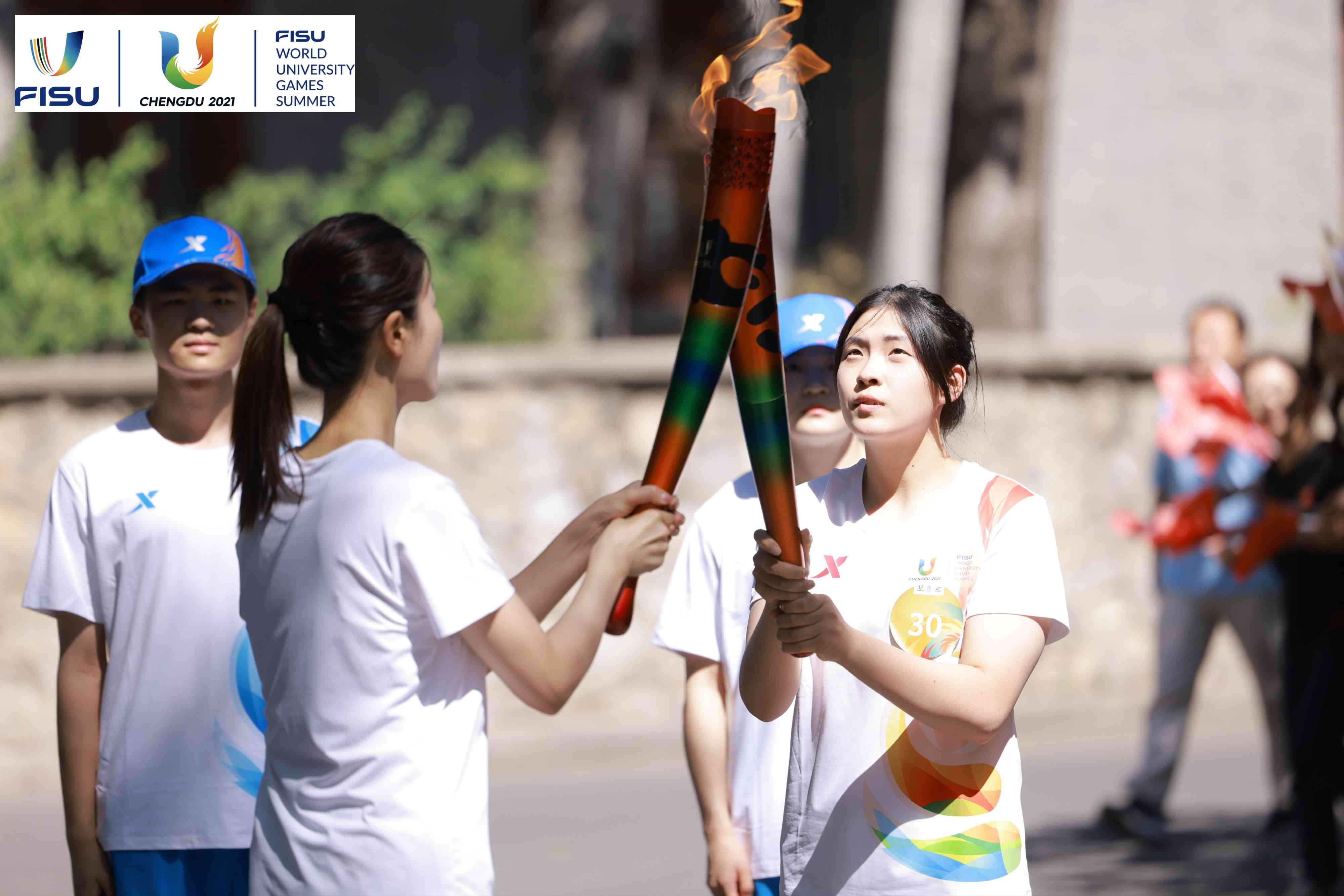 兩名大運會火炬手進行火炬?zhèn)鬟f。 圖片來源：成都大運會執(zhí)委會供圖