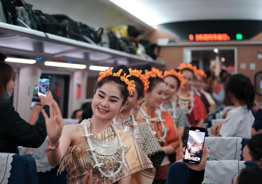 2023年4月13日，老撾工作人員在D887次國際旅客列車上表演。當(dāng)日，中老鐵路從中國昆明南站、老撾萬象站雙向?qū)﹂_D887次和D888次國際旅客列車，兩地乘火車可當(dāng)日通達。中老鐵路是高質(zhì)量共建“一帶一路”的標(biāo)志性工程。新華社記者 邢廣利 攝