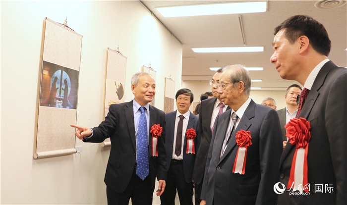 “湖州印象”攝影展主創(chuàng)、世界華人攝影協(xié)會副會長馮學敏向吳江浩大使、福田康夫前首相等嘉賓介紹展出作品。（人民網(wǎng) 許可攝）