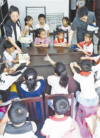  圖④：法院干警為留守兒童發(fā)放暑假讀物。
