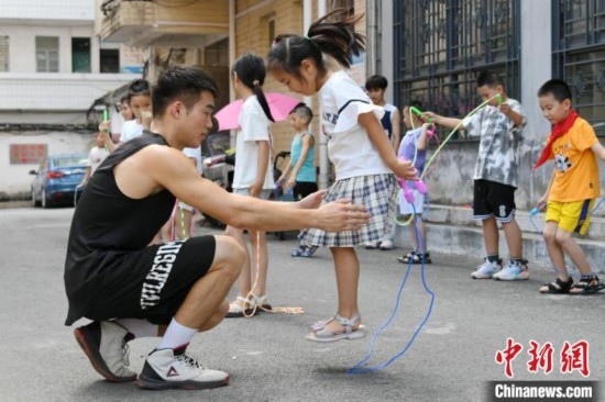 圖為大學生志愿者在教孩子們學跳繩。廖光福 攝