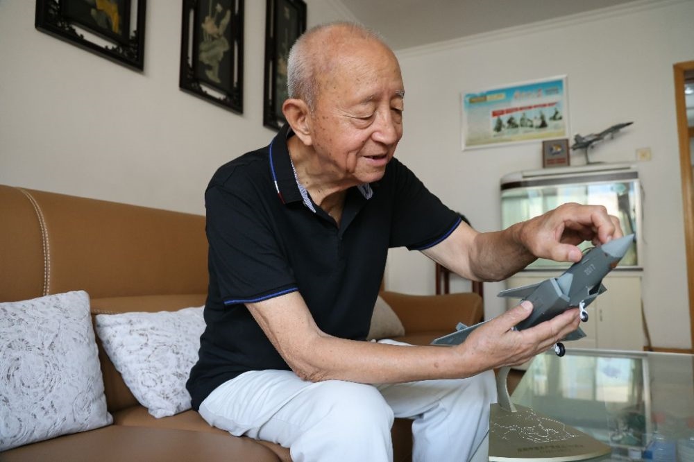 ↑2023年7月24日，新中國(guó)第一代飛行員陶偉在家中擦拭殲-20飛機(jī)模型。新華社發(fā)（張瑞 攝）