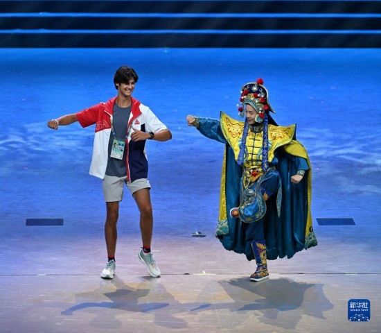 7月29日，美國運動員杜恩（左）在聯(lián)歡會現(xiàn)場與川劇演員互動。新華社記者 蔡湘鑫 攝