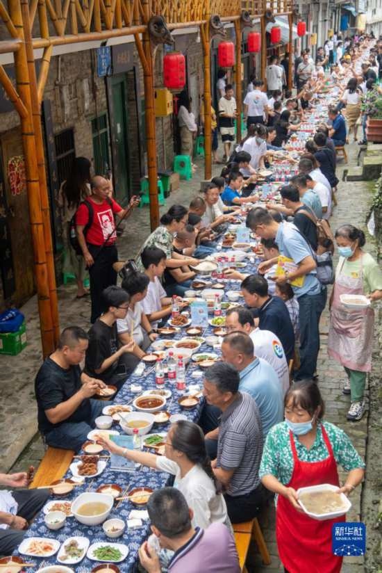 7月29日，在重慶市綦江區(qū)安穩(wěn)鎮(zhèn)，人們在“苗家伏羊節(jié)”上吃長桌宴。新華社記者 唐奕 攝