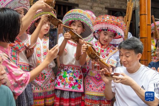 7月29日，在重慶市綦江區(qū)安穩(wěn)鎮(zhèn)，當?shù)鼐用裨凇懊缂曳蚬?jié)”上用傳統(tǒng)習(xí)俗向游客表達祝福。新華社記者 唐奕 攝