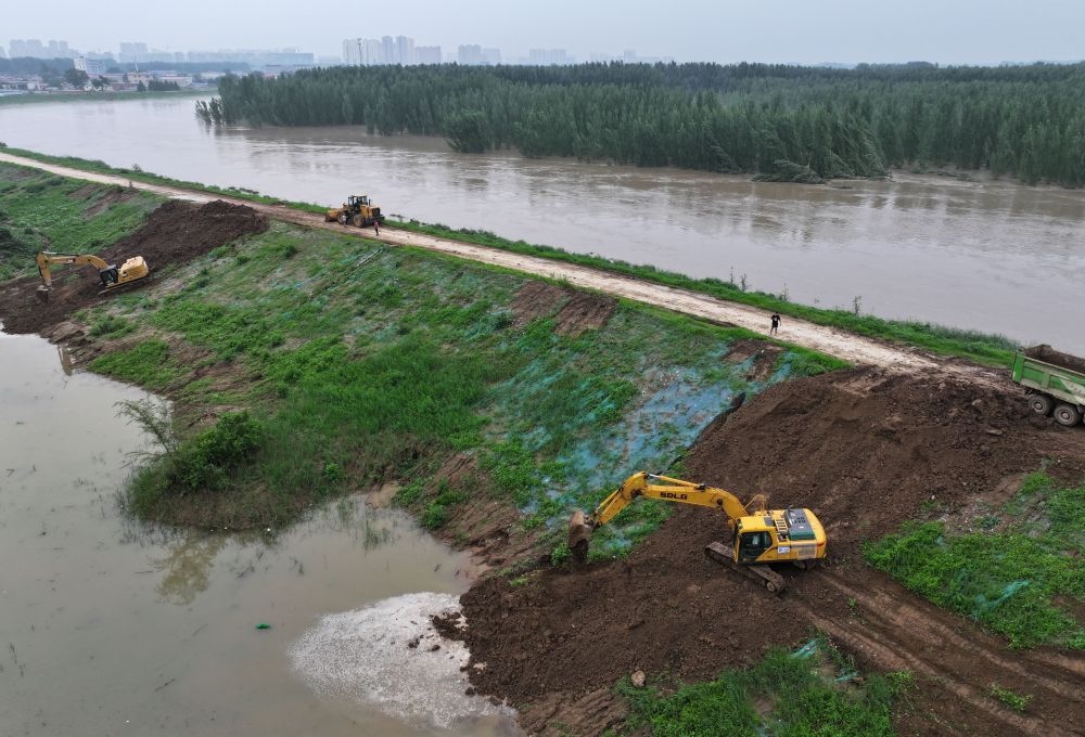 工人操作機(jī)械在白溝河左堤白溝新城高橋村段進(jìn)行除險(xiǎn)加固作業(yè)（8月4日攝，無(wú)人機(jī)照片）。新華社記者 朱旭東 攝