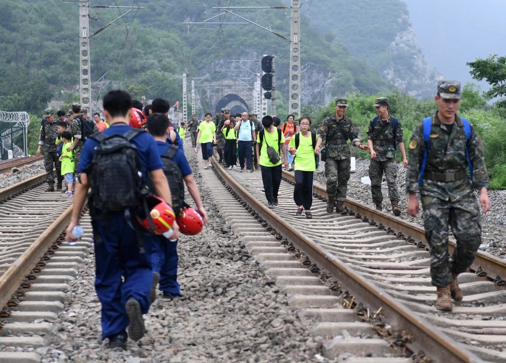 8月2日，部分滯留在北京市門頭溝山區(qū)受困列車的旅客，在救援人員幫助下前往轉(zhuǎn)運客車。新華社記者張晨霖 攝
