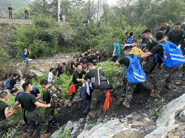 8月2日，Z180次受困列車(chē)的旅客在武警北京總隊(duì)機(jī)動(dòng)第三支隊(duì)官兵的幫助下徒步前往轉(zhuǎn)運(yùn)客車(chē)（手機(jī)照片）。新華社記者 王艷剛 攝