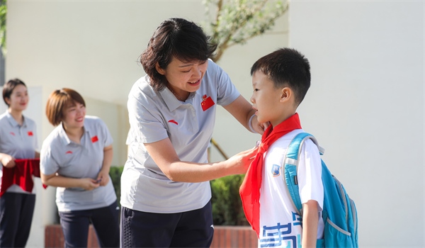 8月30日，雄安史家胡同小學(xué)學(xué)生體驗學(xué)校生活。老師為學(xué)生佩戴?；?。