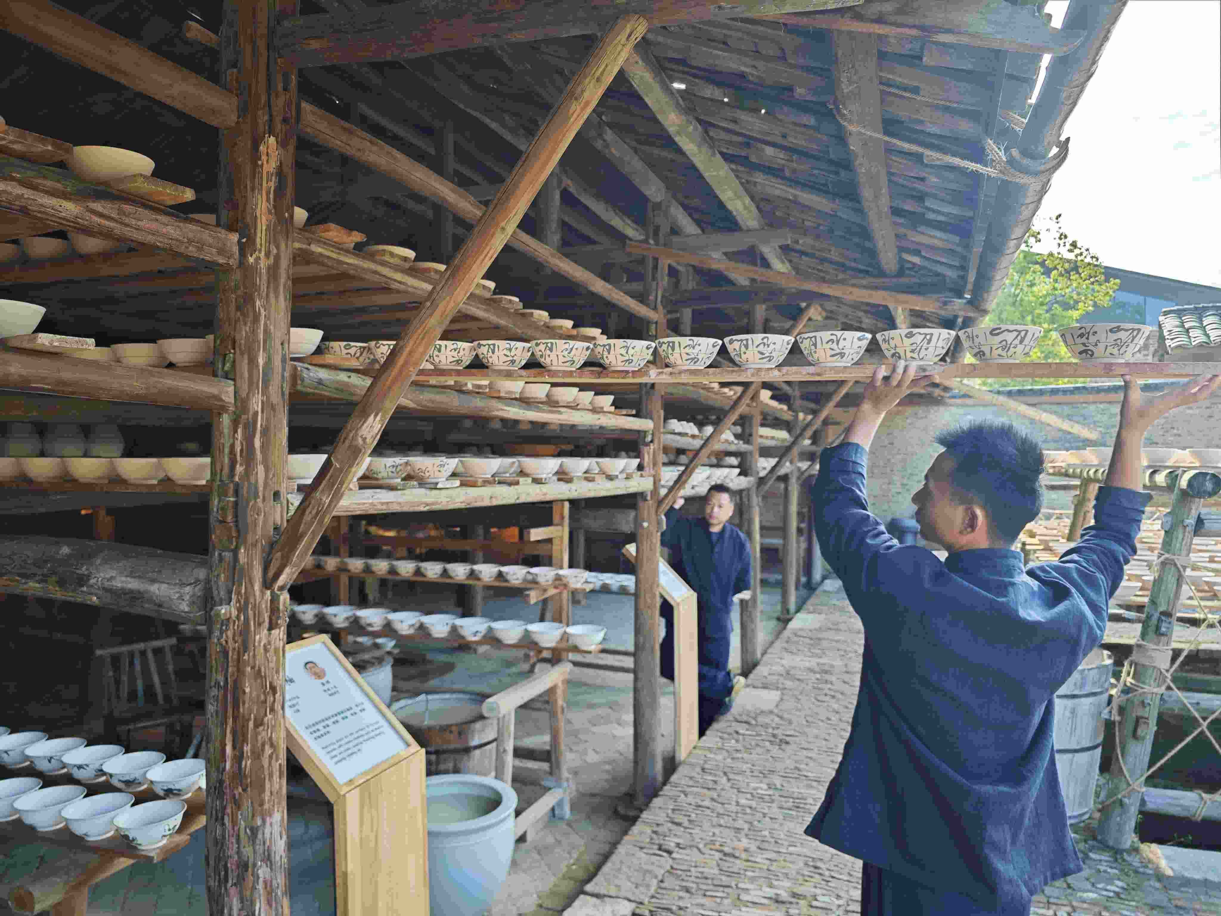 △陶陽里歷史文化街區(qū)里，工匠將陶瓷工藝品放到架上晾干。（總臺央視記者彭漢明拍攝）