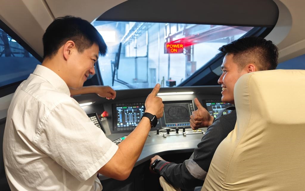 8月25日，在印度尼西亞萬隆的雅萬高鐵德卡魯爾動(dòng)車所內(nèi)，中國師傅穆振（左）在向印尼火車司機(jī)塞蒂亞萬講解動(dòng)車組出庫前的上電作業(yè)。