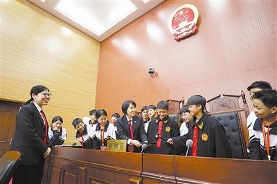 圖③：同學們穿法袍、敲法槌，爭做“小法官”。