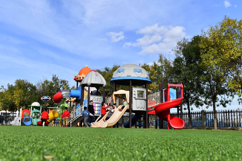 在山東省東營市墾利區(qū)楊廟社區(qū)幼兒園，孩子們在老師的帶領(lǐng)下進行戶外活動（2021年10月19日攝）。新華社記者 郭緒雷 攝