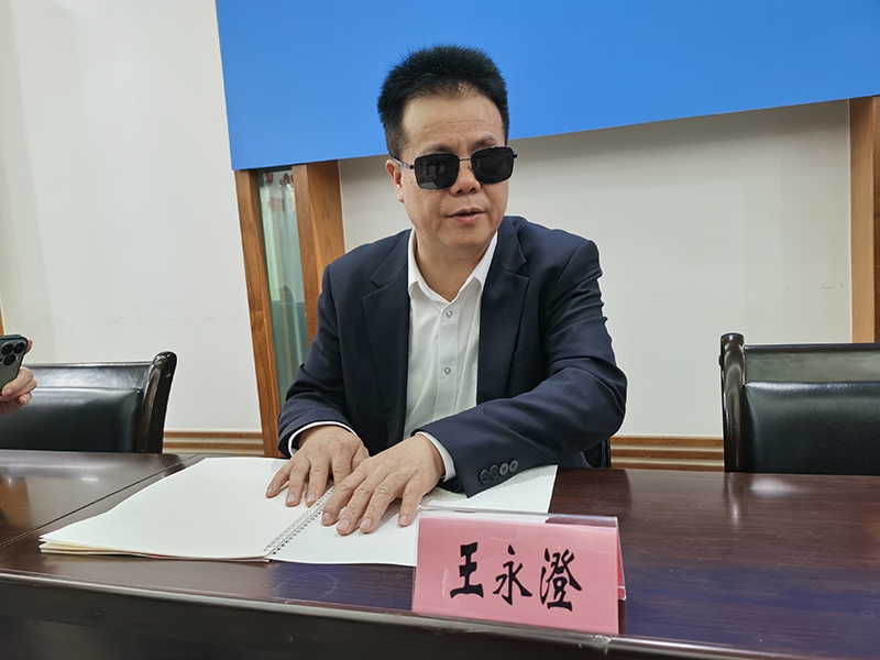 全國(guó)人大代表王永澄正在閱讀盲文版代表建議答復(fù)。本報(bào)記者 張 璁?dāng)z