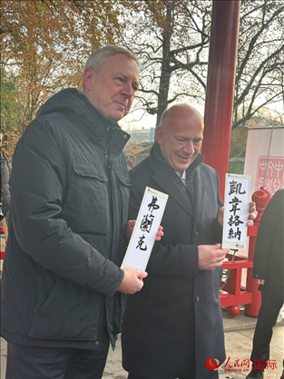 柏林市長韋格納（右）、動物園監(jiān)事會主席布魯克曼（左）手持中國文化中心工作人員現(xiàn)場手書的中文名字。人民網(wǎng)記者 徐馨攝