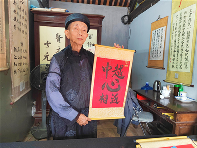 越南首都河內文廟內，阮明珠展示“中越心相近”書法作品。
