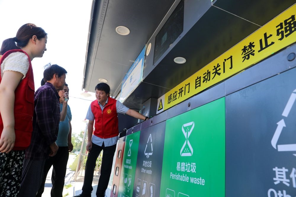 在安徽省合肥市長豐縣莊墓鎮(zhèn)棗林社區(qū)，志愿者指導(dǎo)居民使用智能垃圾分類回收設(shè)備（2023年9月1日攝）。新華社記者 曹力 攝