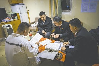 圖②：法官向船長講解相關(guān)法律規(guī)定，查看船舶資料，并與船方辦理扣押船舶的手續(xù)。