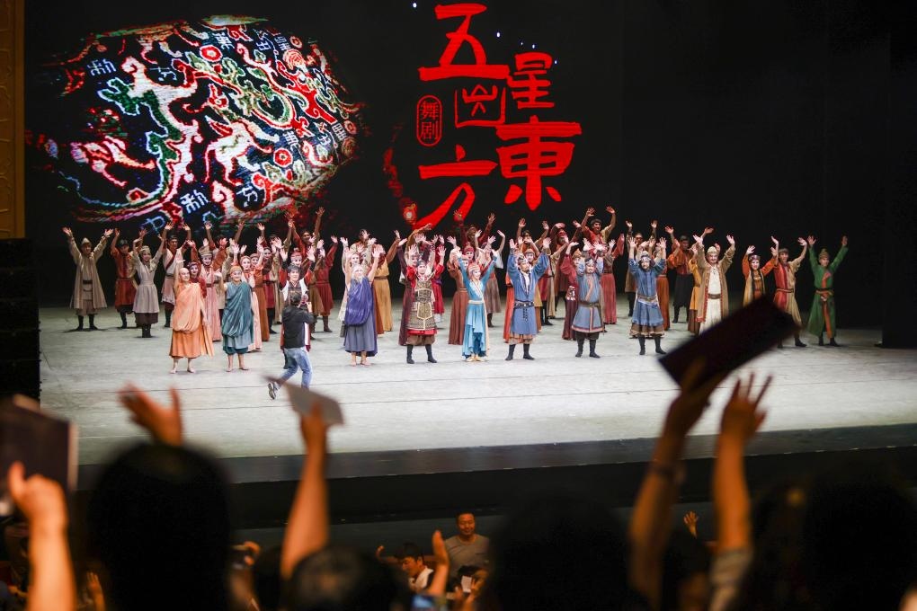 2023年7月31日，新疆和田地區(qū)新玉歌舞團在烏魯木齊京劇院演出舞劇《五星出東方》后和觀眾互相揮手致意。這場演出是第六屆中國新疆國際民族舞蹈節(jié)的參演劇目之一，曾榮獲國家“文華獎”等。新華社記者 郝昭 攝