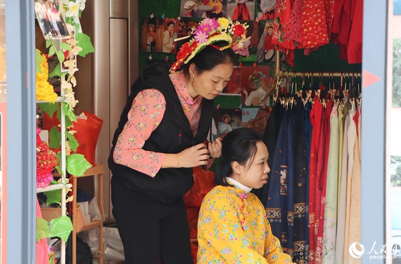 泉州府文廟附近，一名店主正為過(guò)路游客梳理頭發(fā)以佩戴“簪花圍”。人民網(wǎng) 黃東儀攝