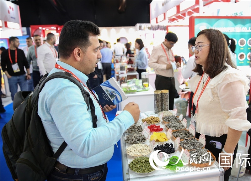 圖為一家中國干果參展企業(yè)代表與采購商洽談。人民網(wǎng) 塔里克·易卜拉欣攝