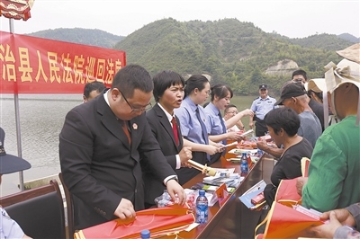 法院干警及相關(guān)部門工作人員對群眾進行生態(tài)環(huán)境保護普法教育。