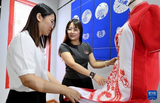 5月31日，在衡水市阜城縣一家剪紙工作室，游客在觀賞帶有剪紙元素的旗袍。