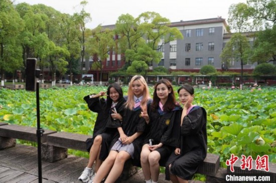 6月19日，時值一年畢業(yè)季，四川大學望江校區(qū)荷花池里的荷花盛開，成為了畢業(yè)生們的打卡圣地，吸引了眾多畢業(yè)生拍照留念。圖為畢業(yè)生在荷花池邊拍照留念。中新社記者 安源 攝