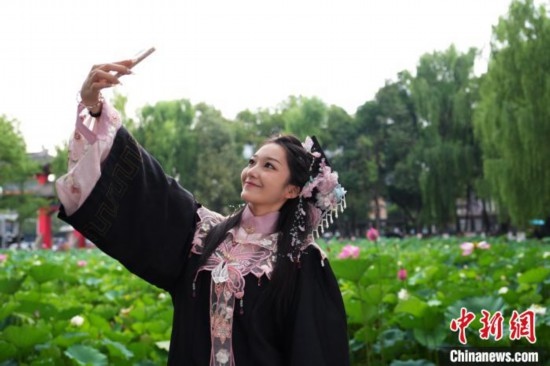 6月19日，時值一年畢業(yè)季，四川大學望江校區(qū)荷花池里的荷花盛開，成為了畢業(yè)生們的打卡圣地，吸引了眾多畢業(yè)生拍照留念。圖為畢業(yè)生在荷花池邊拍照留念。中新社記者 安源 攝