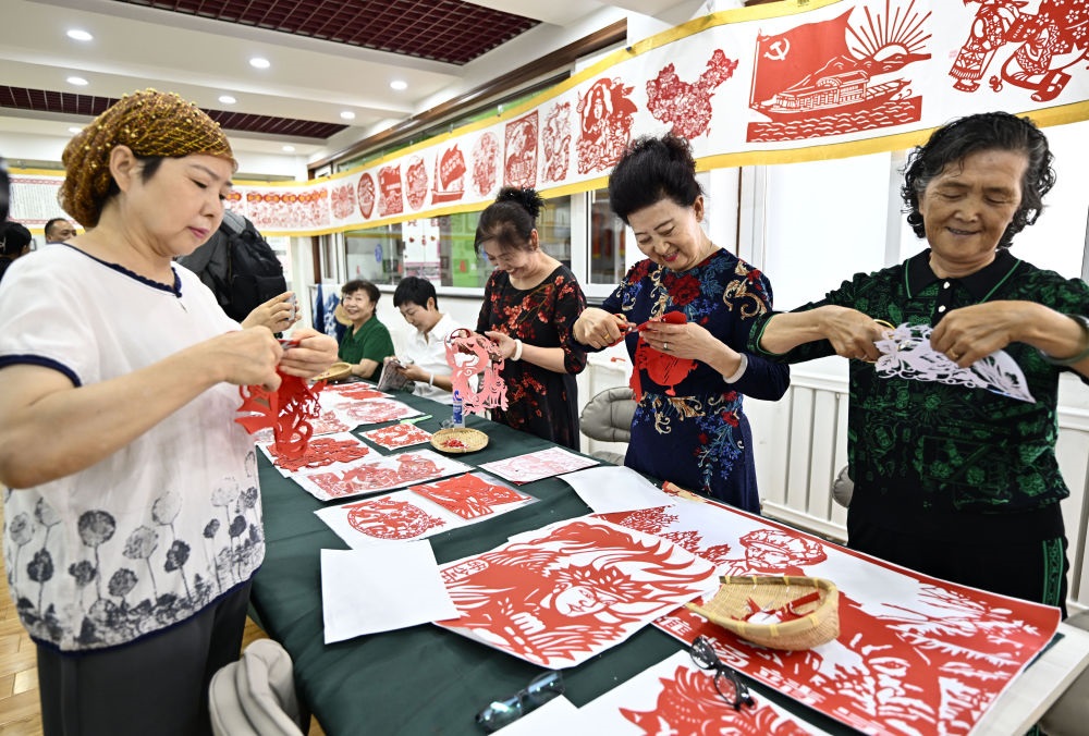 6月19日，長(zhǎng)城花園社區(qū)居民在社區(qū)“才藝堂”制作剪紙。