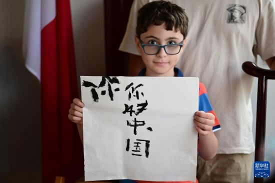 7月4日，在馬耳他桑塔露琪亞市的中國(guó)古典園林“靜園”，一名男孩展示他的書法作品。新華社發(fā)（喬納森·博格 攝）