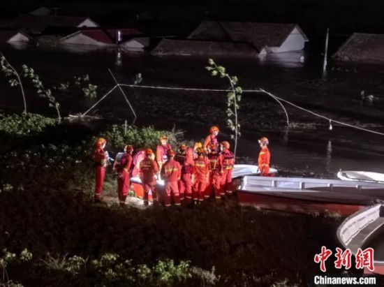  7月6日凌晨3時，在湖南岳陽華容縣團洲垸洞庭湖一線堤防，救援人員剛剛完成一次救援任務，遠處是被淹的民房。中新社記者 白祖偕 攝