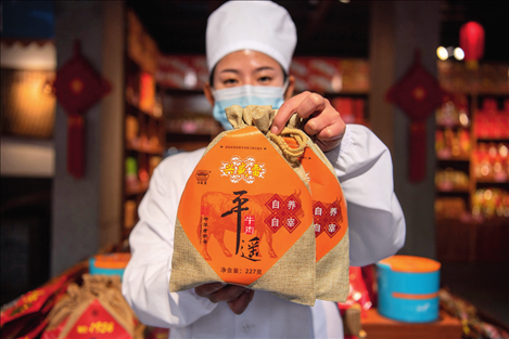 在位于山西省晉中市平遙縣的平遙古城南大街的一家平遙牛肉店內(nèi)，工作人員展示一款牛肉產(chǎn)品（資料照片）楊晨光攝 / 本刊