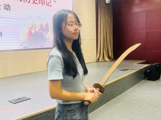 圖為南開大學(xué)社會實踐隊學(xué)生代表呼月紅在學(xué)術(shù)交流活動現(xiàn)場，展示河間調(diào)研行中獲贈的一戰(zhàn)華工蔡世春曾使用過的一把大刀。林卓瑋 攝
