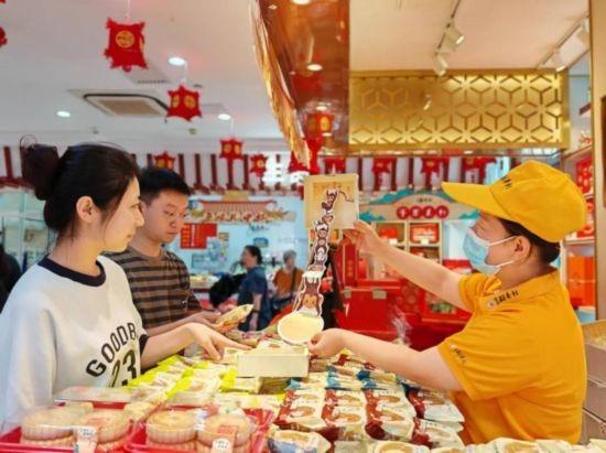 北京稻香村一家門(mén)店內(nèi)，售貨員向顧客展示新上市的月餅禮盒。（受訪者供圖）