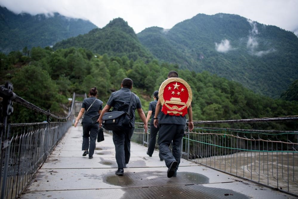 云南省怒江傈僳族自治州貢山縣人民法院法官鄧興背著國(guó)徽與同事們跨過(guò)怒江（2019年8月30日攝）。怒江高山峽谷眾多，交通不便，為方便群眾、更好地開(kāi)展法律服務(wù)，背著國(guó)徽攀高山、過(guò)索橋、躲落石、鉆老林……成為鄧興法官的工作常態(tài)。新華社記者 江文耀 攝
