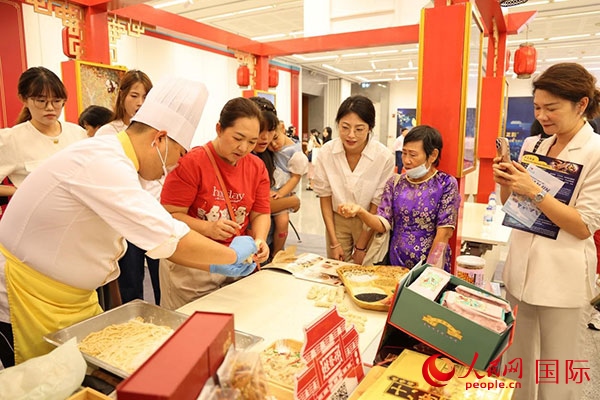 演出前，在天津桂發(fā)祥十八街麻花制作技藝非遺體驗展臺前，泰國民眾體驗天津麻花制作。人民網(wǎng)記者 楊一攝