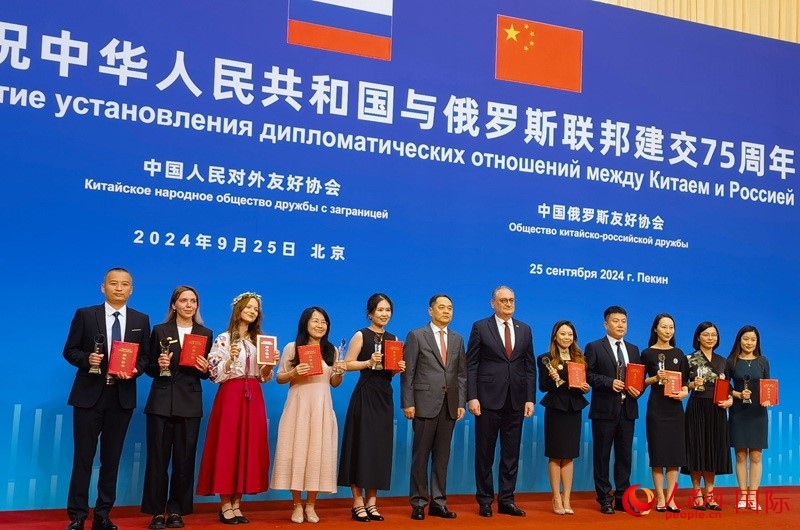 楊萬(wàn)明會(huì)長(zhǎng)和莫爾古洛夫大使為10位中俄青年友好微視頻創(chuàng)意大賽獲獎(jiǎng)代表頒獎(jiǎng)。人民網(wǎng)記者 李明琪攝