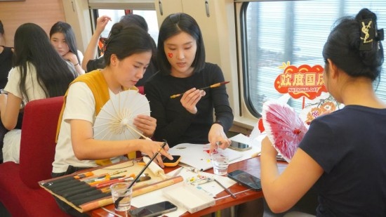 10月1日，旅客們在G1634次列車上給油紙傘作畫。新華社記者周義 攝