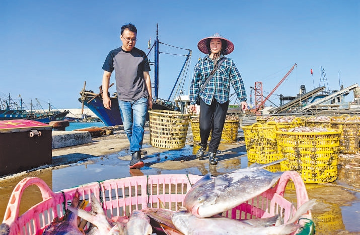 許小斌（左）和漁民一起搬運(yùn)海鮮。本報(bào)記者 付 文攝