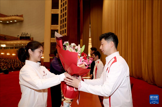 11月15日，一名學(xué)生代表在報(bào)告會(huì)上向乒乓球運(yùn)動(dòng)員馬龍（右）獻(xiàn)花。新華社記者 李明 攝