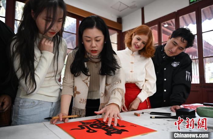 1月20日，西泠印社社員李硯（左二）為外籍留學生講述蛇年福字貼創(chuàng)作靈感。當日，來自巴西、馬來西亞、加納、哈薩克斯坦的外籍留學生在浙江杭州西泠印社體驗福貼、春聯和篆刻，感受古老的中國傳統(tǒng)文化。中新社記者 王剛 攝