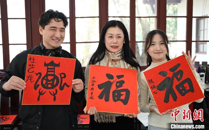 1月20日，外籍留學生和西泠印社社員李硯(中)展示各自創(chuàng)作的福貼。當日，來自巴西、馬來西亞、加納、哈薩克斯坦的外籍留學生在浙江杭州西泠印社體驗福貼、春聯和篆刻，感受古老的中國傳統(tǒng)文化。中新社記者 王剛 攝