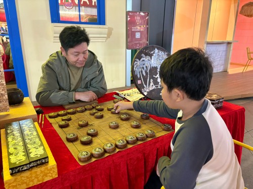 柯秋楓與市民下椰雕象棋。人民網(wǎng) 陳葉欣攝