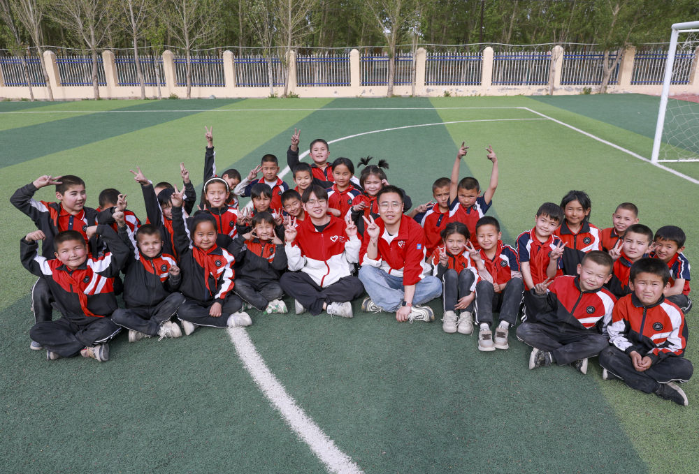 4月23日，在新疆克州阿圖什市哈拉峻鄉(xiāng)謝依特小學(xué)，支教教師王俊文（中左）、李軻凡（中右）和學(xué)生在一起。